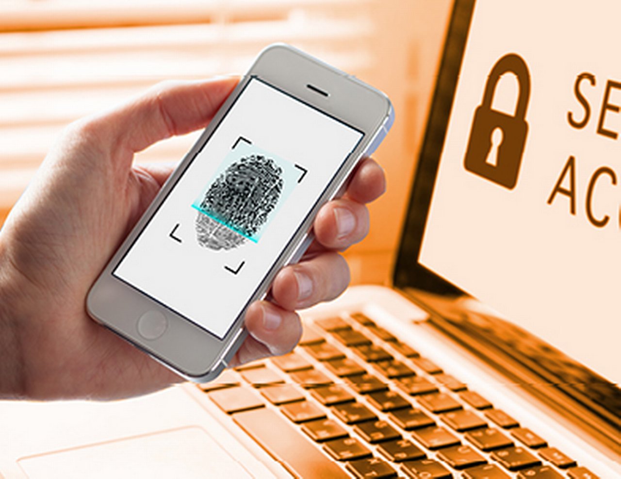 Hand hält vor einem Laptop ein Smartphone hoch, auf dem ein Fingerabdruckscan gezeigt wird.