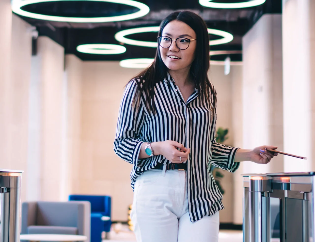 Woman presenting an access card while walking through office security turnstiles