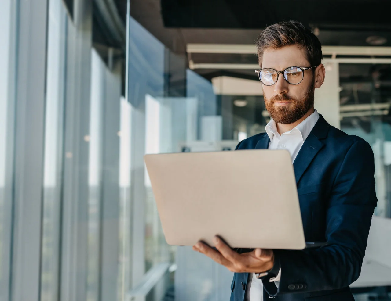 Businessman holding an open laptop in a modern office