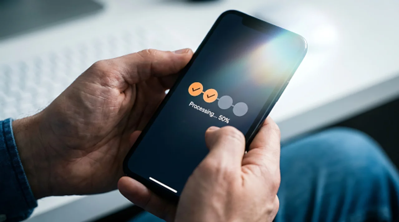 Person hält ein Smartphone mit einer angezeigten Fortschrittsanzeige beim Verarbeiten