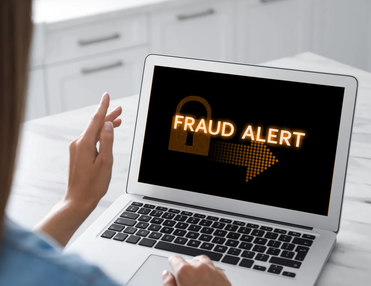 Person viewing a laptop screen displaying a fraud alert with a padlock symbol
