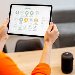 Person holding a tablet with a user interface for controlling smart home devices