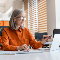 Businesswoman using a laptop while holding a smartphone at her desk